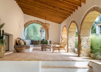 Galería reformada con arcos de piedra y techo de madera en estilo mediterráneo