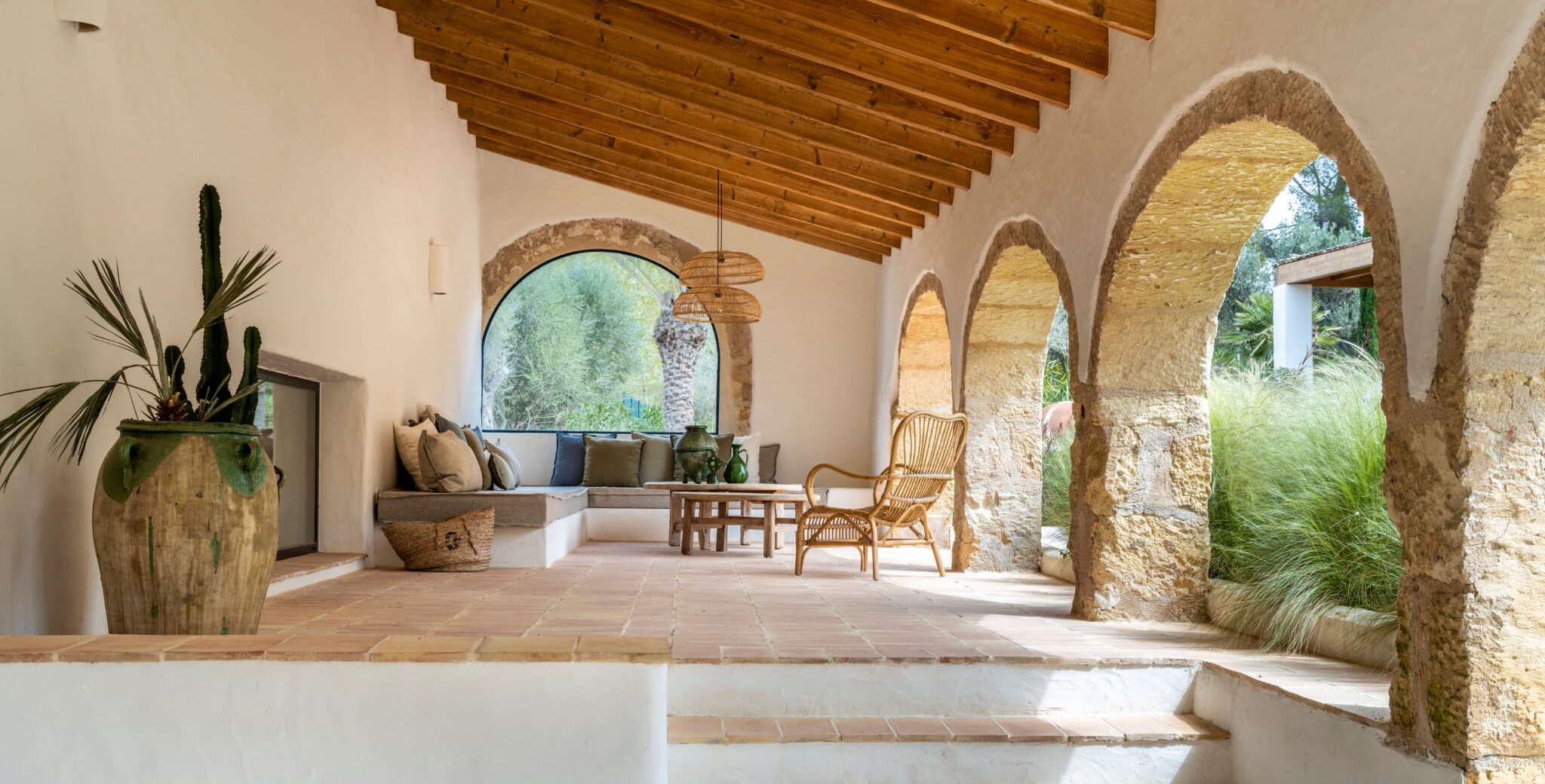 Galería reformada con arcos de piedra y techo de madera en estilo mediterráneo